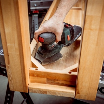 Máquina de lixamento Bosch em madeira clara sobre suporte metálico