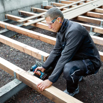 Homem a aparafusar estrutura de madeira com máquina elétrica