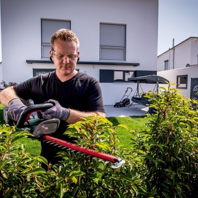 Homem a podar arbustos com tesoura eléctrica