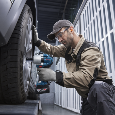 Homem a usar chave de impacto Bosch para desmontar roda de carro numa oficina