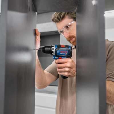 Parafusadeira Bosch azul e preta em uso por homem