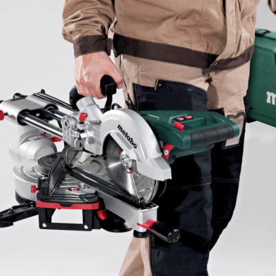 Serra de corte Metabo com mala de transporte verde e trabalhador a segurar ambos.