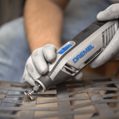 Ferramenta rotativa DREMEL cinzenta usada para cortar grelha metálica preta.