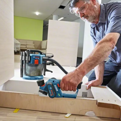 Homem a usar ferramenta elétrica azul e preta para trabalhar numa estrutura de madeira clara