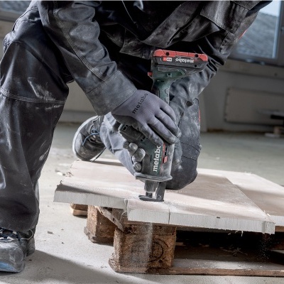 Pessoa a usar ferramenta elétrica Metabo para cortar madeira numa palete