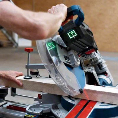 Pessoa a cortar madeira com serra de esquadria em ambiente interior