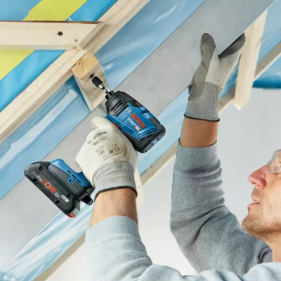 Homem usando parafusadeira Bosch para colocar painel em estrutura de madeira