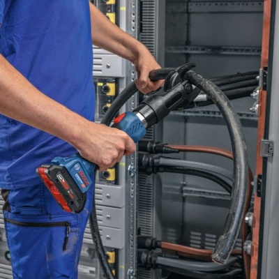 Homem a usar ferramenta elétrica em painel elétrico