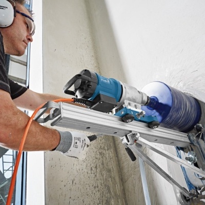 Pessoa a operar máquina perfuradora azul numa parede