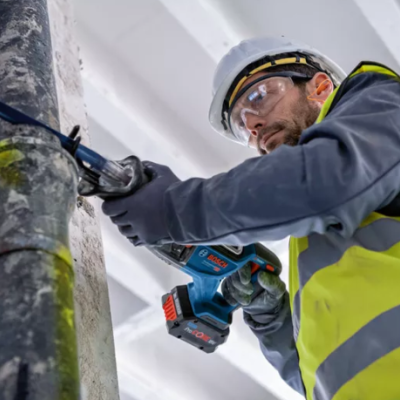 Trabalhador com equipamento de proteção a usar ferramenta elétrica em tubo metálico