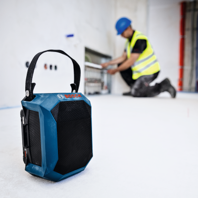 Coluna de som portátil Bosch azul com trabalhador em construção ao fundo