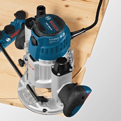 Fresadora Bosch azul e cinzenta sobre madeira clara com fixação.