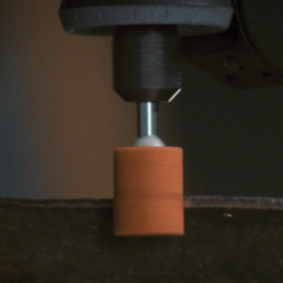 Ferramenta de lixa cilíndrica alaranjada numa máquina ferramental