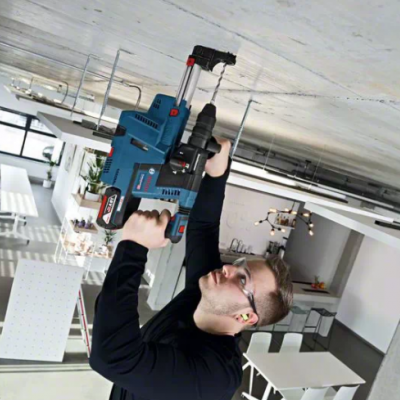 Pessoa a usar furadeira elétrica azul no teto de uma sala moderna branca