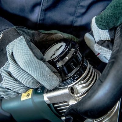 Ferramenta elétrica verde com botões de ajuste nas mãos de pessoa com luvas metabo