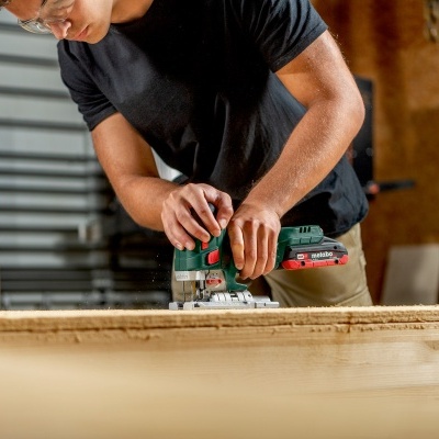 Pessoa a cortar madeira com serra elétrica numa oficina