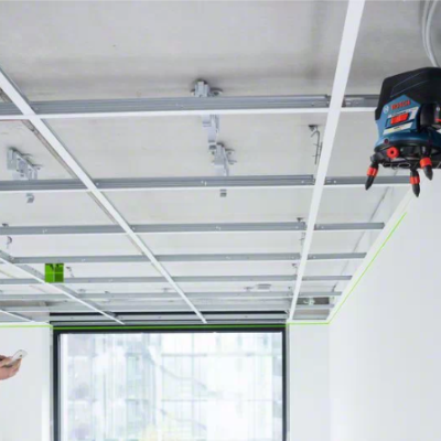 Laser de nível Bosch Professional a emitir linhas verdes numa divisão com homem