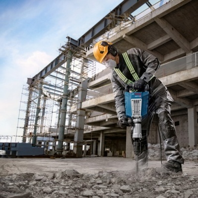 Trabalhador usando martelo perfurador elétrico em construção
