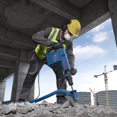 Martelo pneumático azul BOSCH com trabalhador em construção de betão