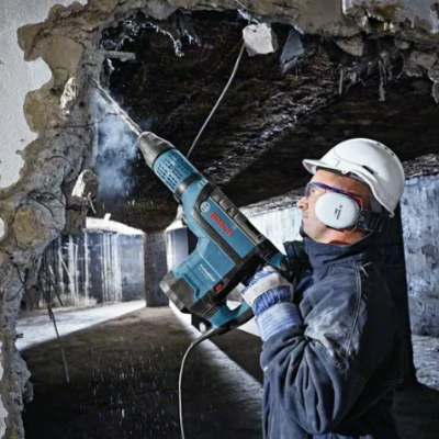 Trabalhador com capacete a usar ferramenta elétrica BOSCH para demolir parede interna