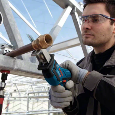 Homem a usar soprador de solda Bosch em canos metálicos, com óculos e luvas num espaço industrial