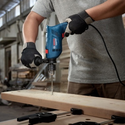 Pessoa a furar madeira com broca elétrica Bosch numa oficina