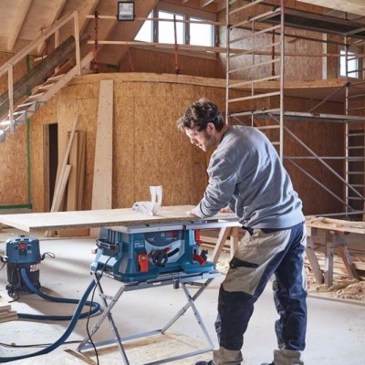 Oficina de carpintaria com homem a trabalhar numa máquina de serrar madeira