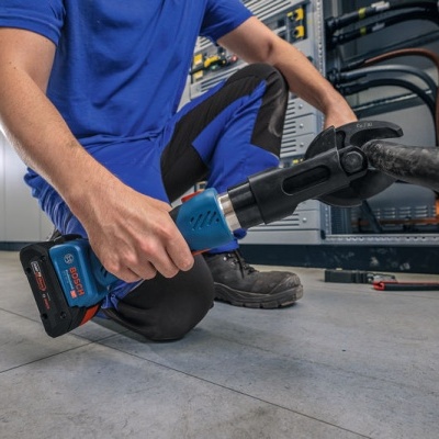 Pessoa a usar ferramenta elétrica Bosch azul e preta para conector grande em ambiente técnico