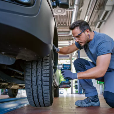 Homem a trabalhar com pneu de carro em oficina automóvel