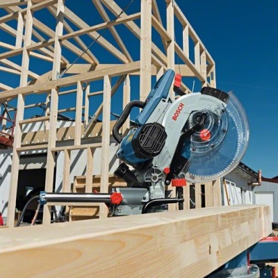 Serra de esquadria elétrica Bosch sobre viga de madeira numa construção ao ar livre