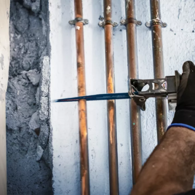 Serra recíproca a cortar tubos de cobre numa parede