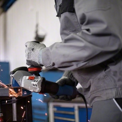 Pessoa a usar rebarbadora elétrica para cortar metal com faíscas em ambiente industrial