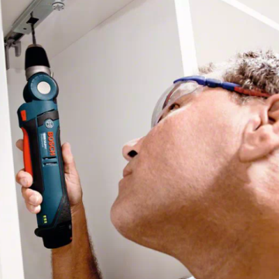 Homem a usar ferramenta elétrica Bosch azul escuro em móvel branco