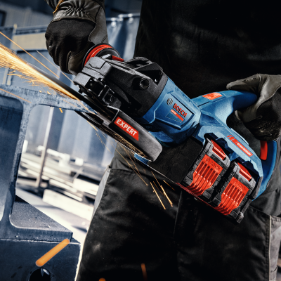 Maquina de esmerilar Bosch azul, preta e vermelha em uso com faíscas.