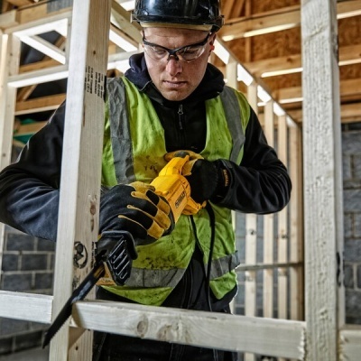 Homem com equipamento de proteção a usar serra elétrica numa obra