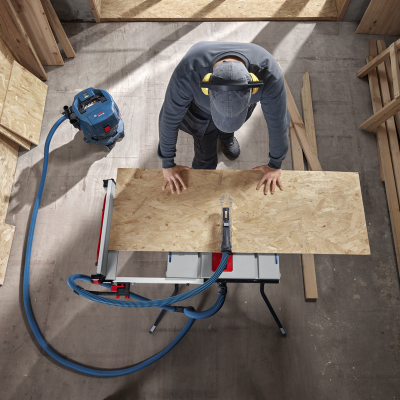 Máquina de cortar madeira com funil azul e homem a segurar chapa de madeira OSB