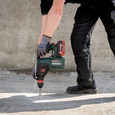 Pessoa a usar furadeira numa superfície de cimento