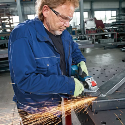 Homem a lixar peça de metal com ferramenta elétrica numa oficina