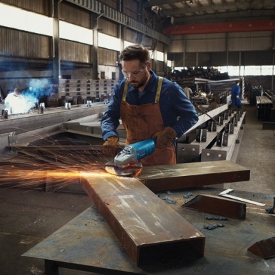 Homem a usar proteção a esmerilhar metal num armazém industrial