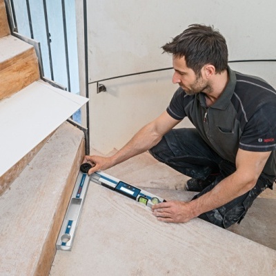 Homem a medir degraus de escada interior com nível