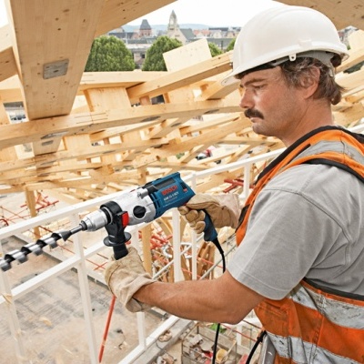 Homem a usar furadeira em estrutura de madeira numa obra