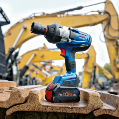 Parafusadora elétrica Bosch azul instalada em maquinaria enferrujada com escavadoras ao fundo