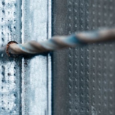 Broca metálica a perfurar chapa de metal com fundo de tijolos