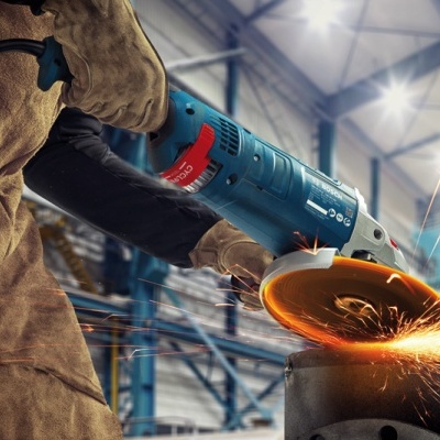 Esmeriladora angular azul a cortar metal com faíscas numa oficina industrial