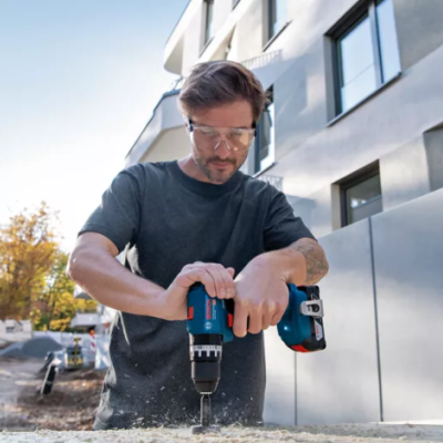 Homem a usar furadeira elétrica em construção exterior