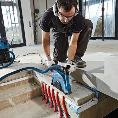 Trabalhador com serra elétrica azul em construção