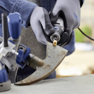 Afiação de ferramenta manual em superfície cinzenta por pessoa com luvas cinzentas