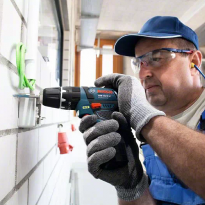 Homem a operar parafusadeira Bosch em parede interior de blocos brancos