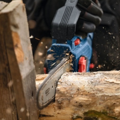 Motosserra elétrica cortando tronco de madeira ao ar livre