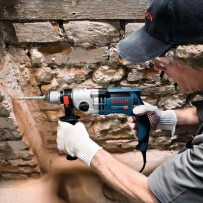 Pessoa a usar ferramenta Bosch para perfurar parede de tijolos